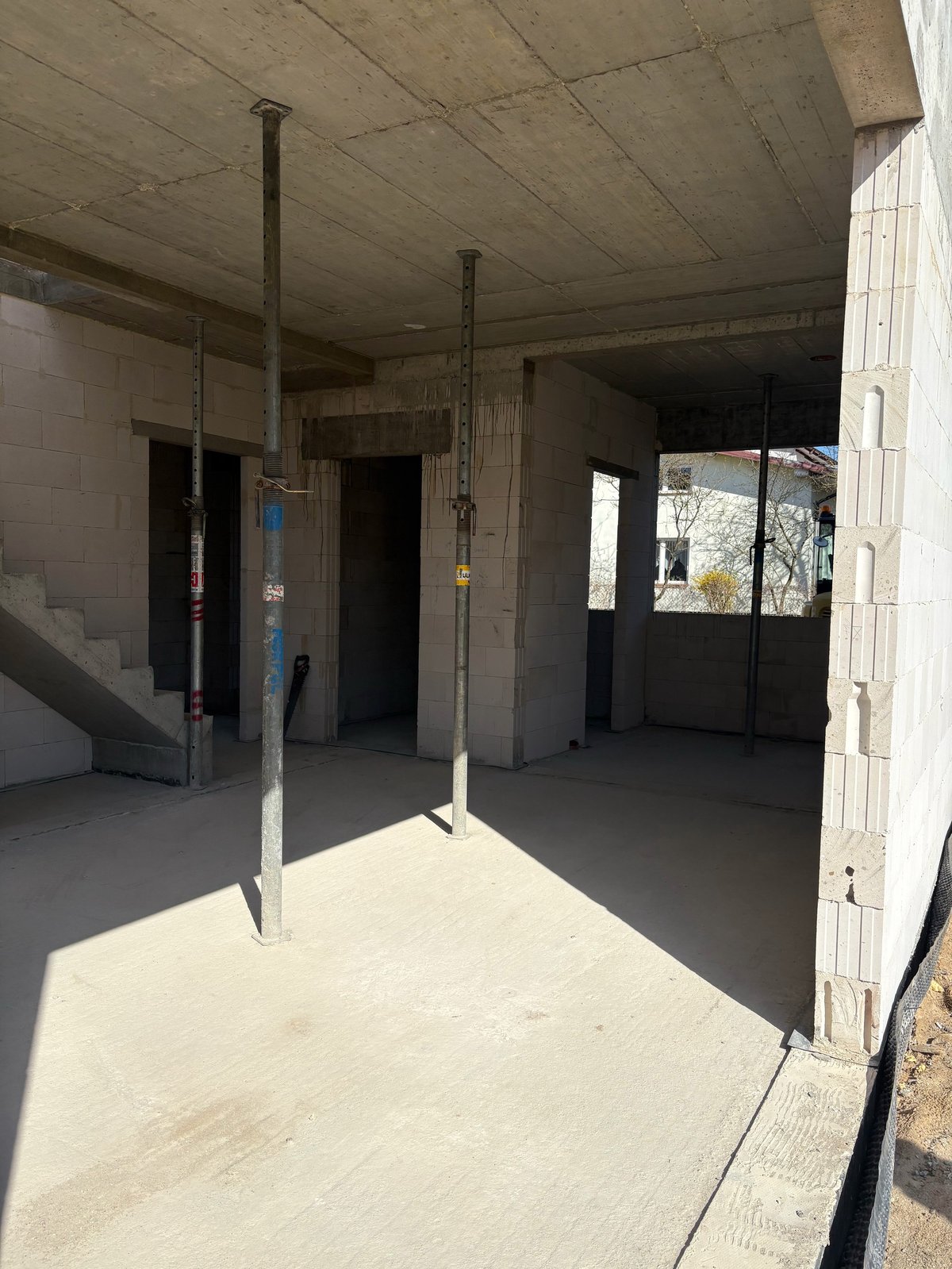 Empty concrete interior space under construction with exposed ceiling, support columns, and doorways visible